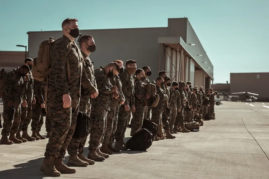 Ilustrasi mimpi latihan hansip — men in black and brown camouflage uniform standing on brown floor