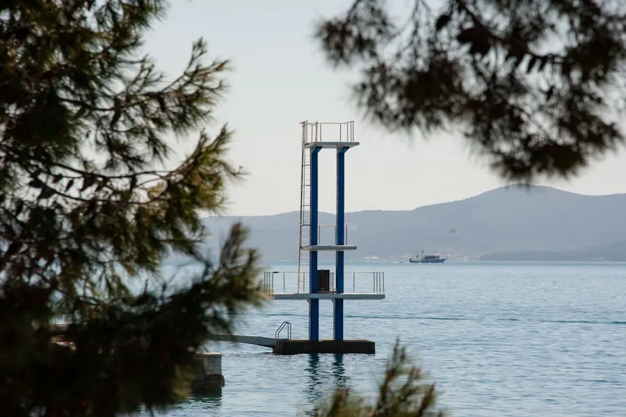 Ilustrasi mimpi loncat indah — a tall tower sitting in the middle of a body of water
