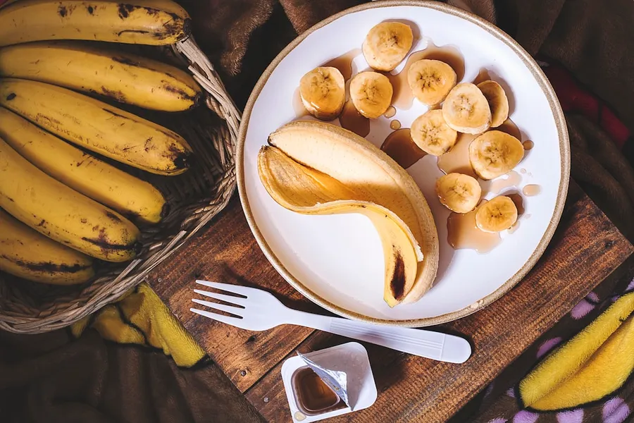 Ilustrasi mimpi makan pisang — sliced ripe banana on round white ceramic plate