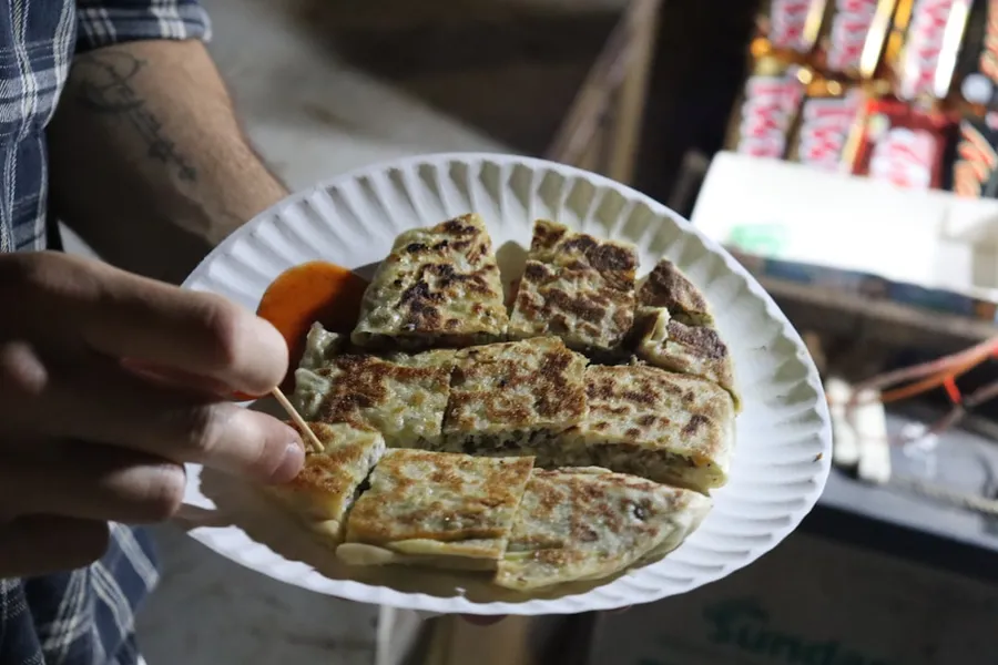 Ilustrasi mimpi martabak telur — A person holding a paper plate with food on it
