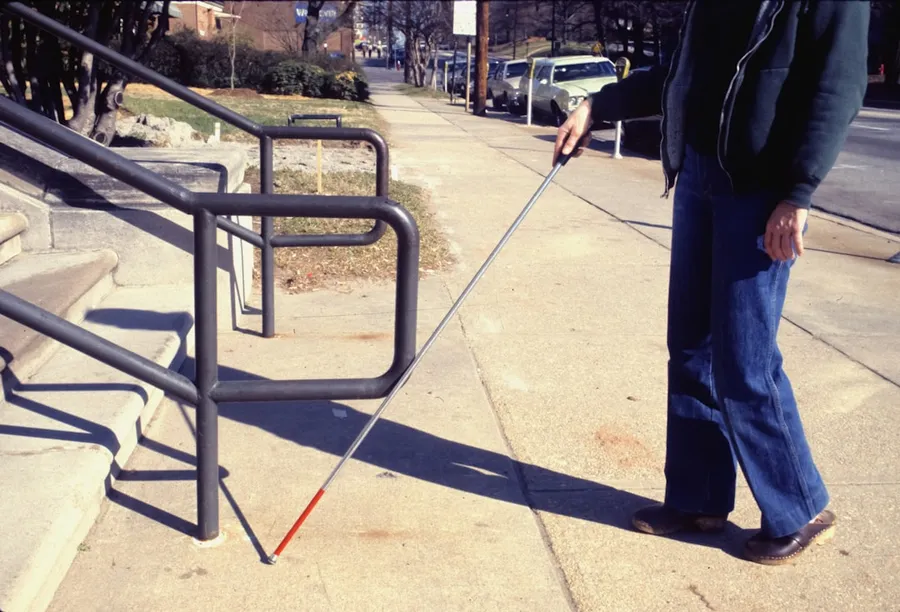 Ilustrasi mimpi mata buta — a man walking a dog on a leash down a sidewalk