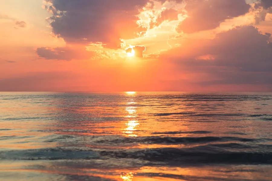 Ilustrasi mimpi matahari terbenam — sea under white clouds at golden hour