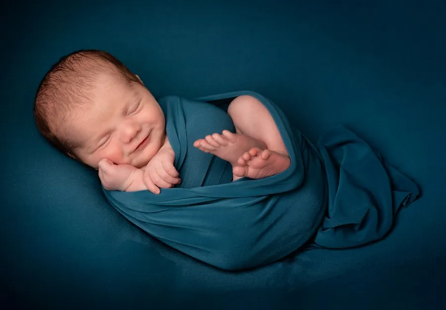Ilustrasi mimpi melahirkan bayi laki-laki — baby lying on blue textile