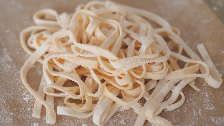 Ilustrasi mimpi memasak mie — white pasta on brown wooden table