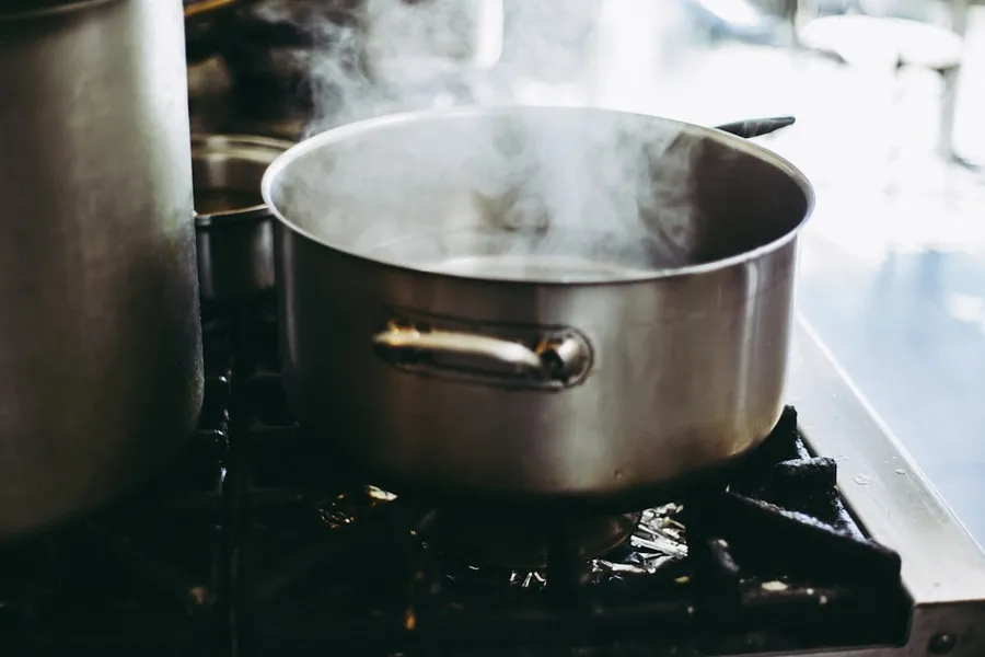 Ilustrasi mimpi memasak nasi — stainless steel cooking pot with lid