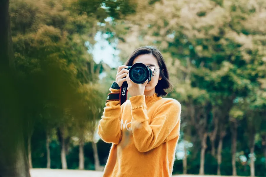Ilustrasi mimpi memotret — woman holding DSLR camera