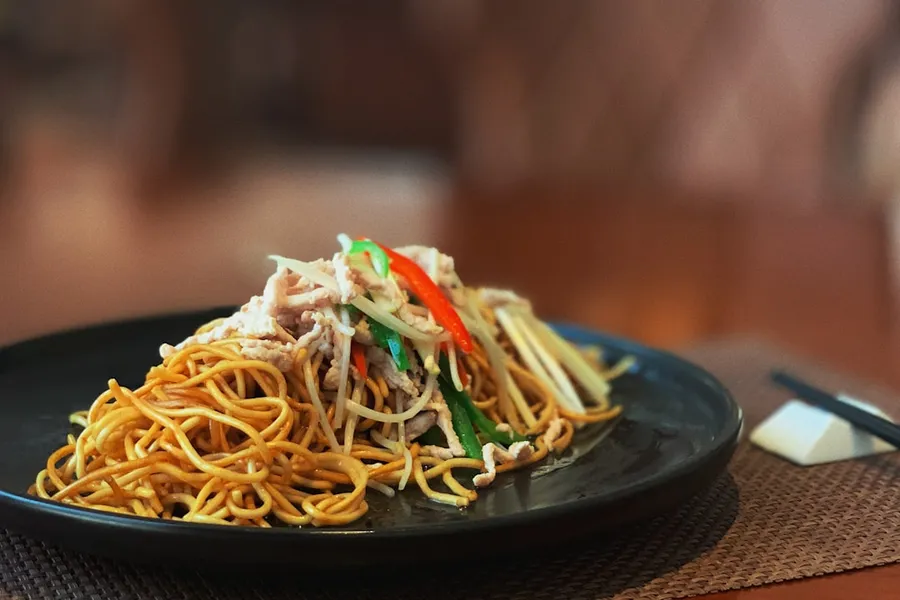 Ilustrasi mimpi mie ayam — pasta dish on black plate