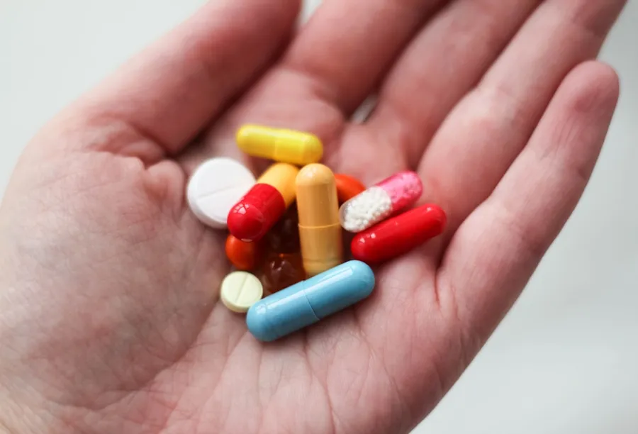 Ilustrasi mimpi minum obat — orange and white medication pill on persons hand