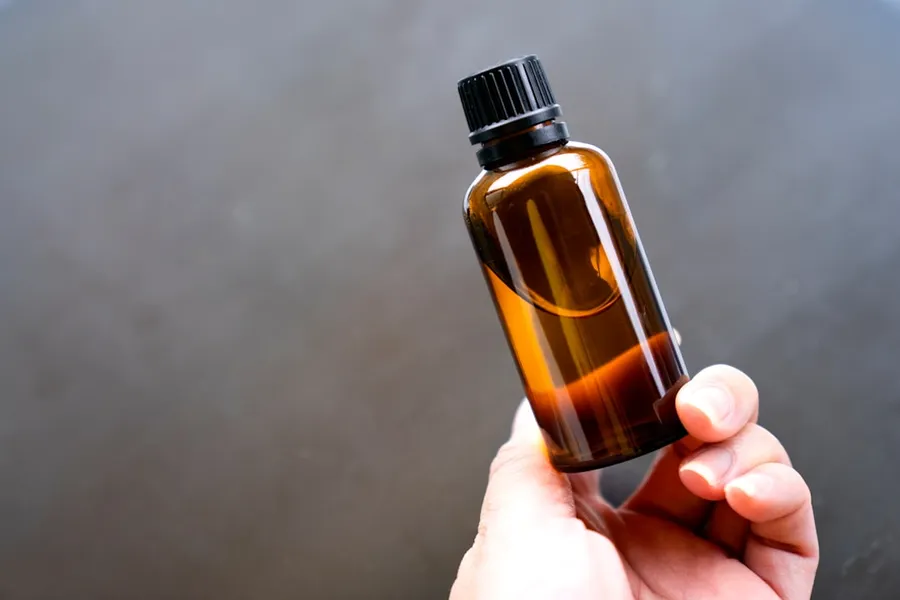 Ilustrasi mimpi minyak rambut — a person holding a bottle of essential oils