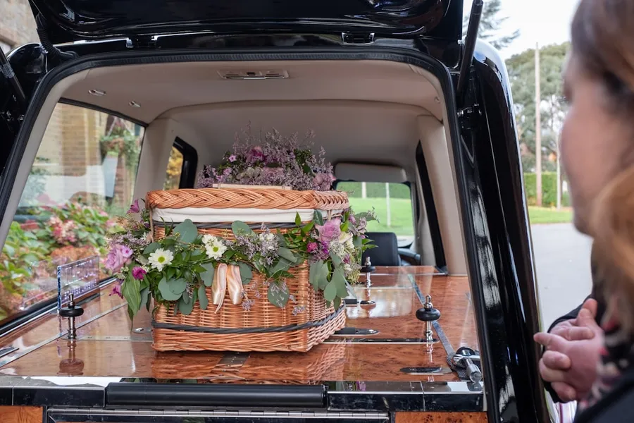 Ilustrasi mimpi mobil jenasah — the back of a van with flowers in the trunk