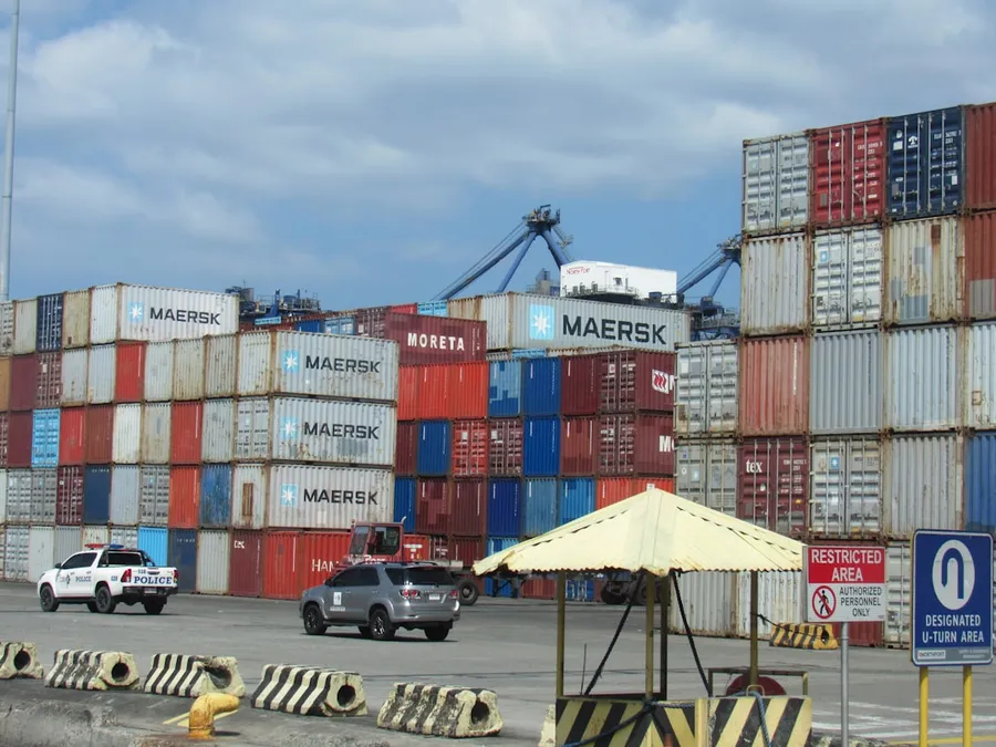 Ilustrasi mimpi mobil kontainer — Stacked shipping containers at a busy port terminal.