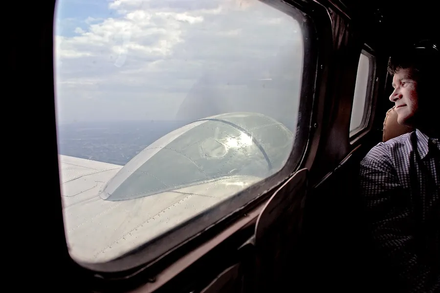 Ilustrasi mimpi naik kapal terbang — Man looking out airplane window at clouds
