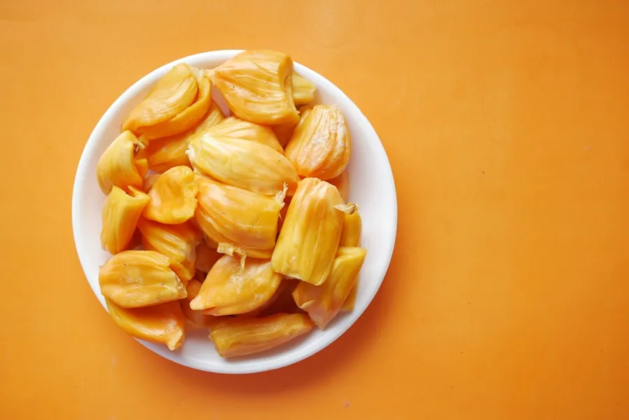 Ilustrasi mimpi nangka — sliced yellow fruit in white ceramic bowl