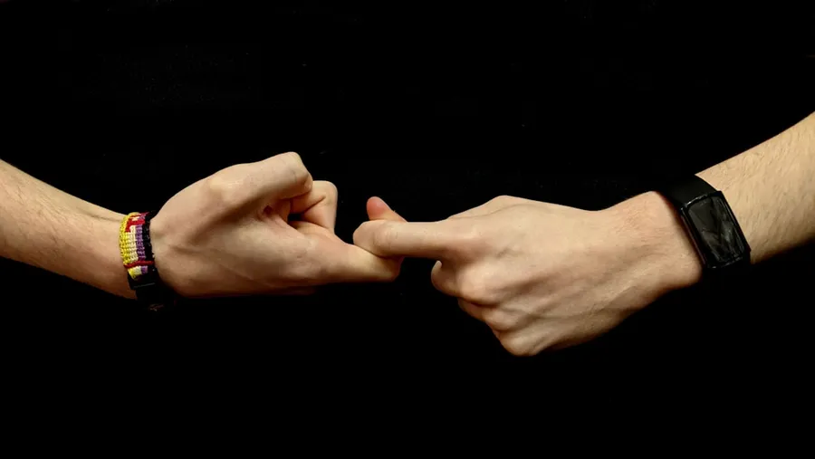 Ilustrasi mimpi orang bisu — two hands holding each other with bracelets on them