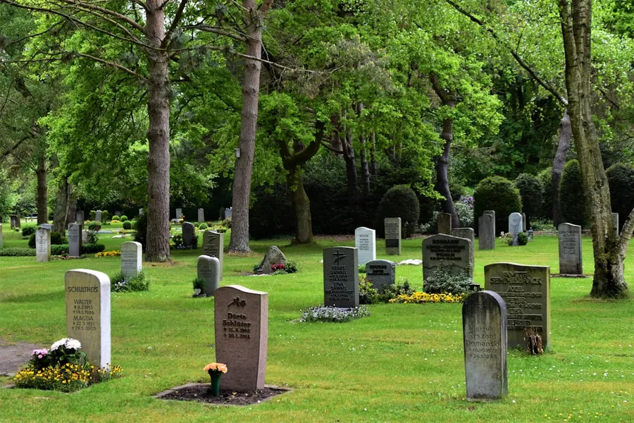 Ilustrasi mimpi orang mati — gray concrete cross on green grass field during daytime