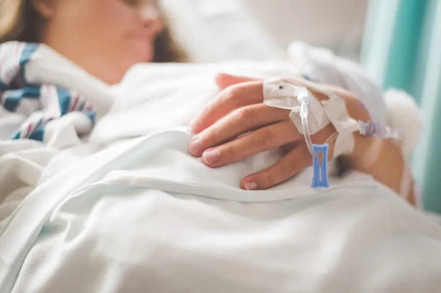 Ilustrasi mimpi orang melahirkan — a woman laying in a hospital bed with an iv in her hand