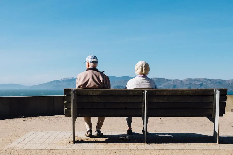 Ilustrasi mimpi jejaka tua — man and woman sitting on bench facing sea