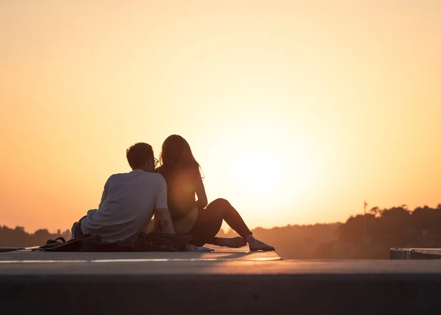 Ilustrasi mimpi pacaran — couple sitting near trees during golden hour