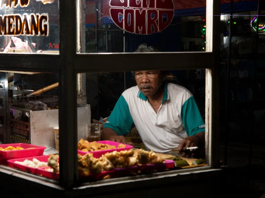 Ilustrasi mimpi penjual gorengan — Man working at a food stall at night