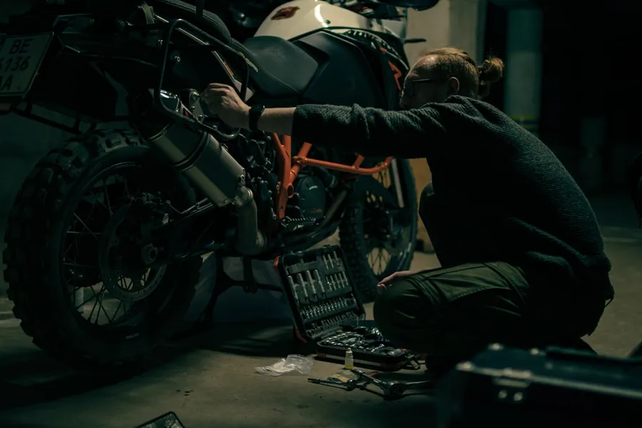 Ilustrasi mimpi perbaiki motor — a man working on a motorcycle in a garage