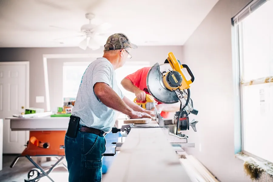 Ilustrasi mimpi perbaiki rumah — man standing infront of miter saw