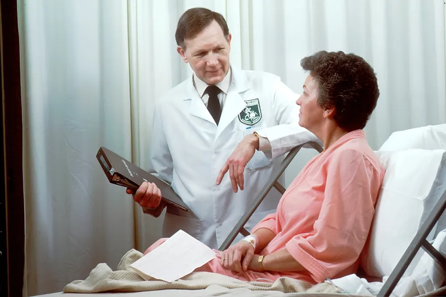 Ilustrasi mimpi periksa dokter — man in white button up shirt holding black tablet computer