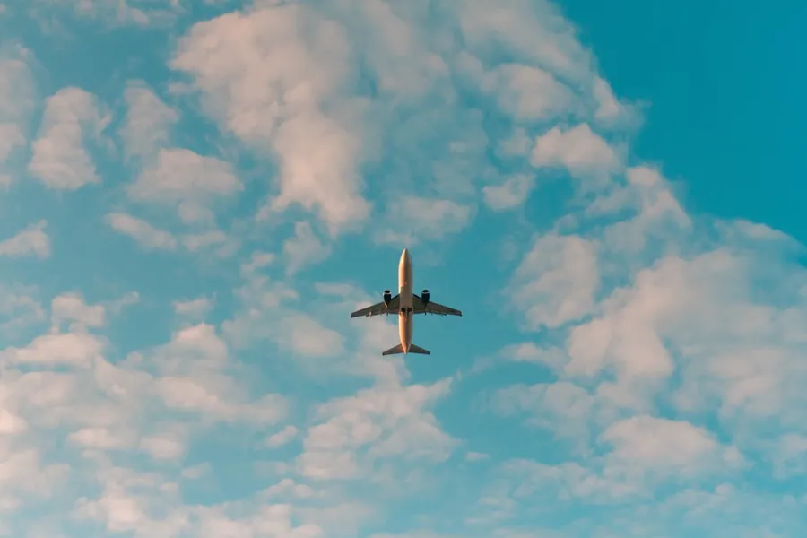 Ilustrasi mimpi pesawat terbang — white airplane flying in the sky during daytime