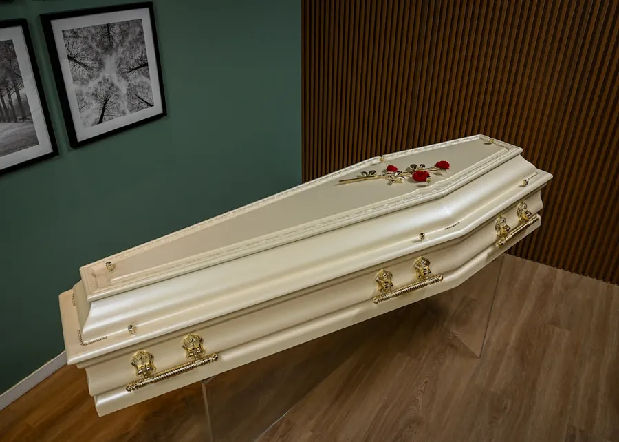Ilustrasi mimpi peti mati — A white casket sitting on top of a hard wood floor