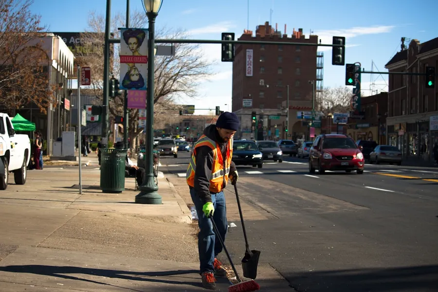 Ilustrasi mimpi petugas kebersihan — man cleaning the road near traffic light