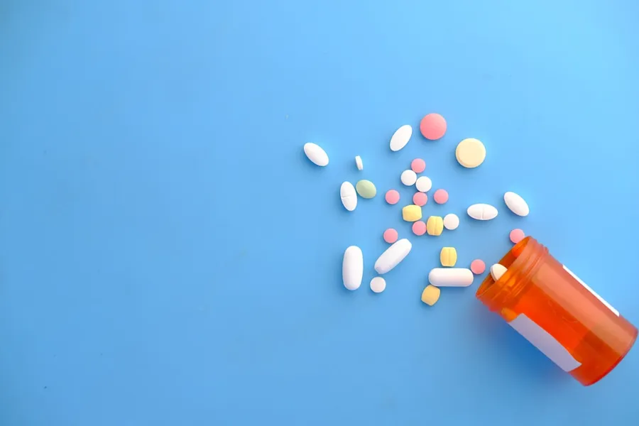 Ilustrasi mimpi pil — colorful pills spilling from orange bottle
