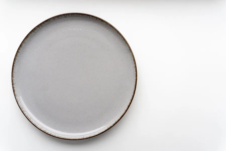 Ilustrasi mimpi piring — a white plate with a brown rim on a white surface