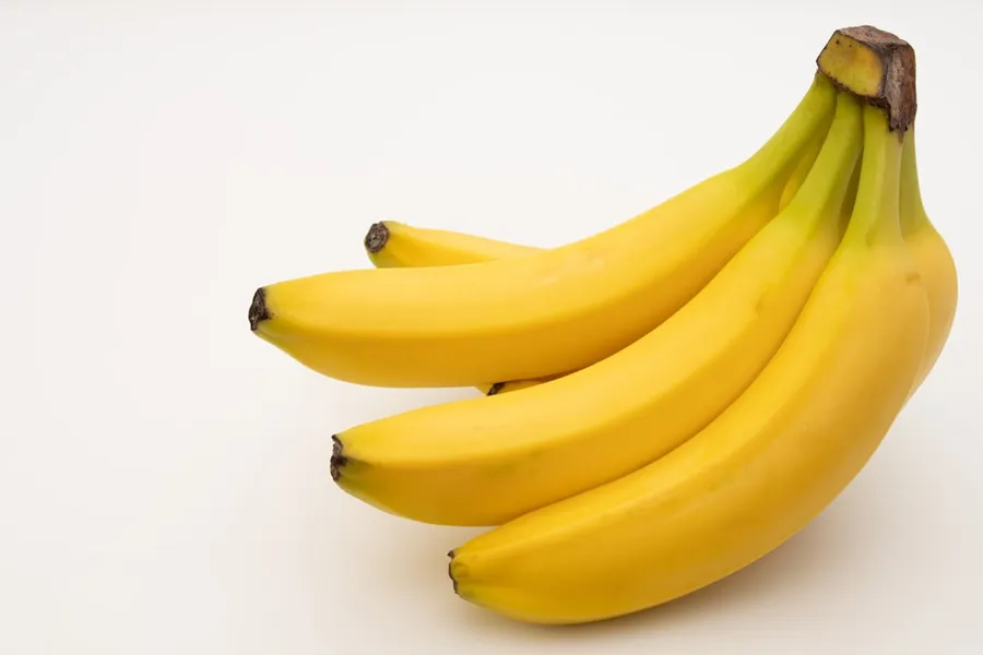 Ilustrasi mimpi pisang — a bunch of bananas sitting on top of a white table