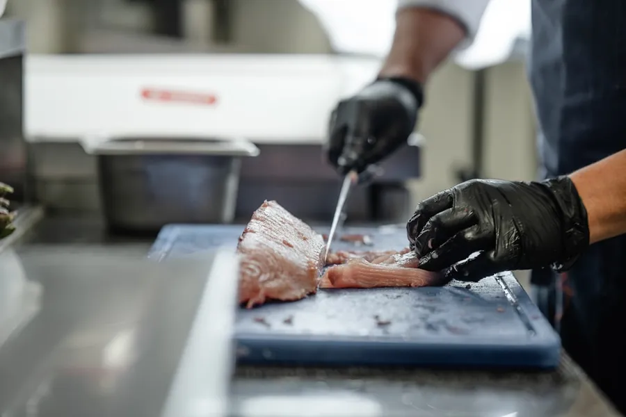 Ilustrasi mimpi potong ikan — A person cutting up a piece of meat on a cutting board