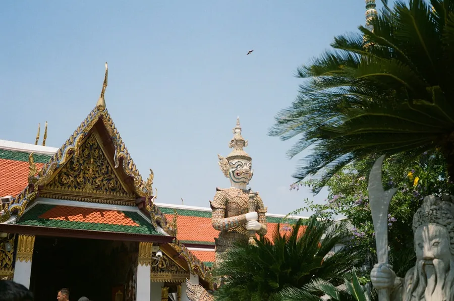 Ilustrasi mimpi raksasa — Ornate temple building with guardian statues and palm trees.