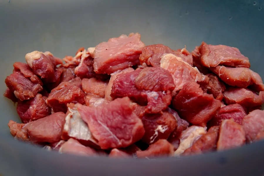 Ilustrasi mimpi rendang daging — raw meat on blue ceramic bowl