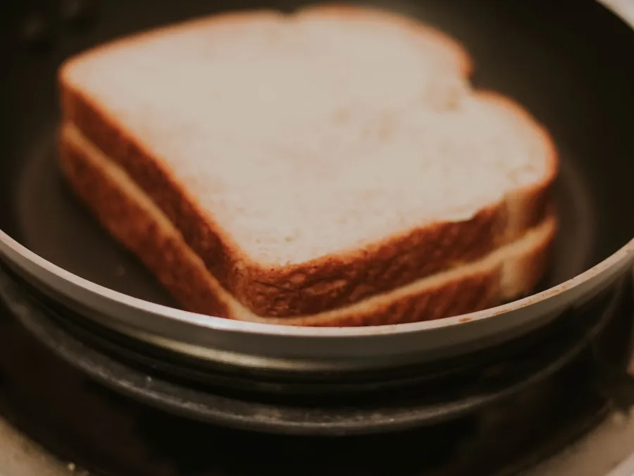 Ilustrasi mimpi roti bakar — a close up of a sandwich in a pan on a stove