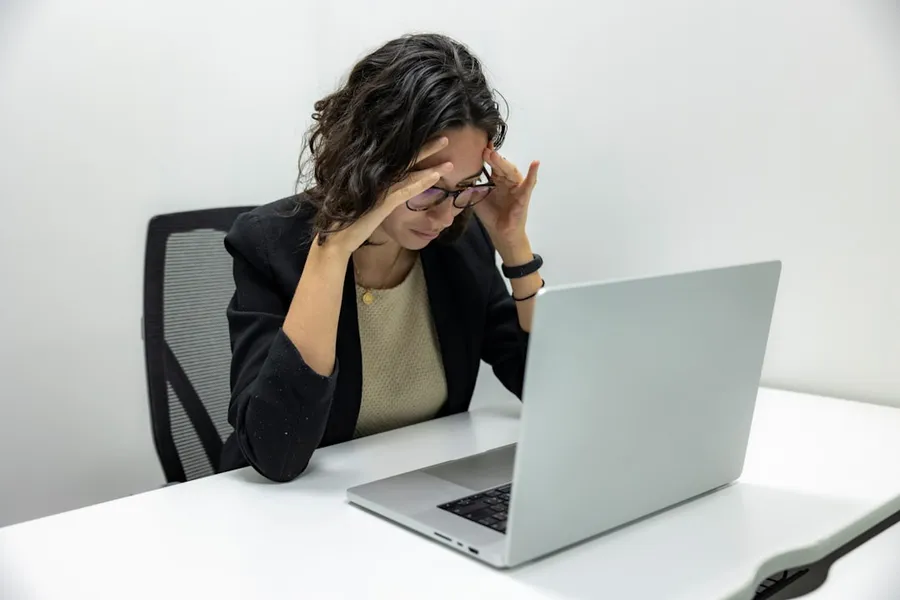 Ilustrasi mimpi sakit kepala — a woman sitting in front of a laptop computer