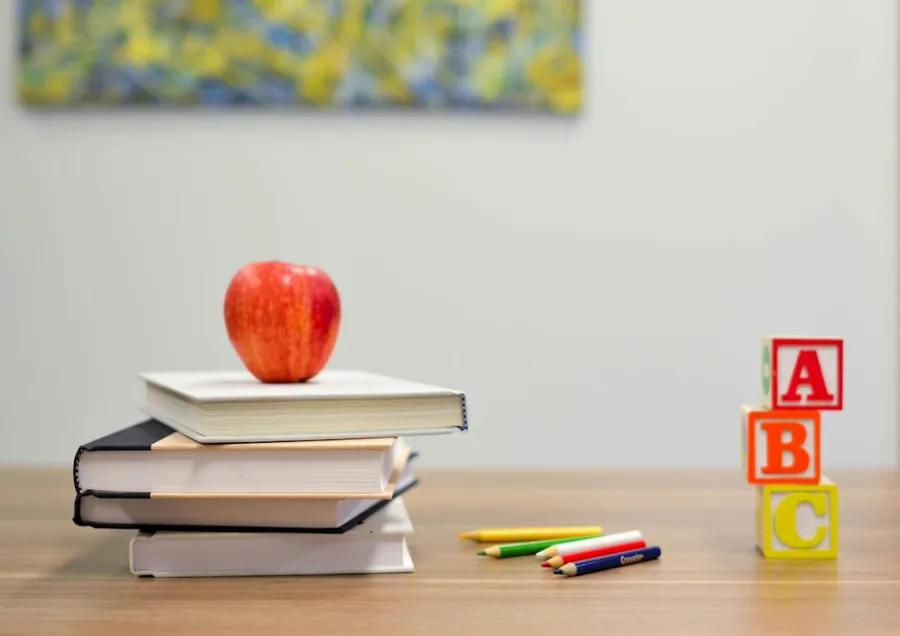 Ilustrasi mimpi ke sekolah — red apple fruit on four pyle books