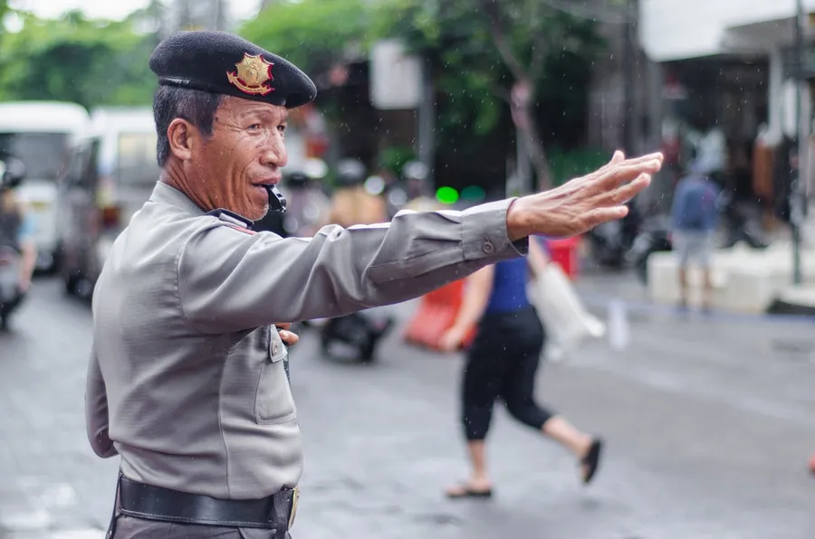 Ilustrasi mimpi sempritan — Police officer directing street traffic while blowing a whistle.