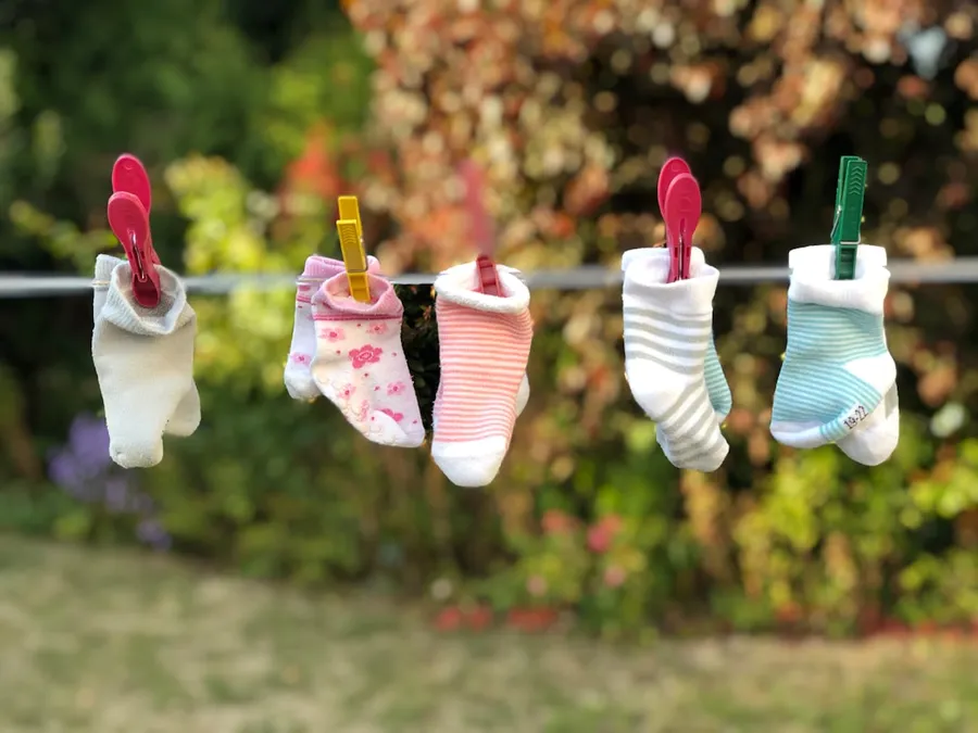 Ilustrasi mimpi sepatu bayi — five pairs of socks pinned on clothesline