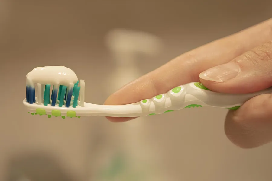 Ilustrasi mimpi sikat gigi — a person is holding a toothbrush with toothpaste on it