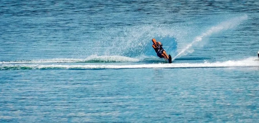 Ilustrasi mimpi ski air — A person on a water ski being pulled by a boat
