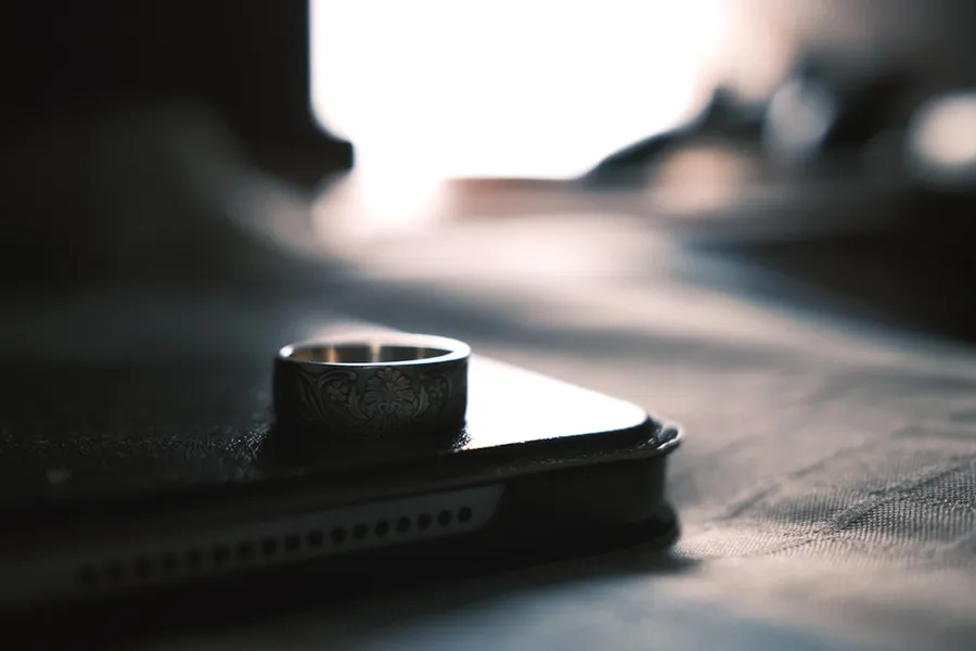 Ilustrasi mimpi suami selingkuh — silver ring on black leather wallet