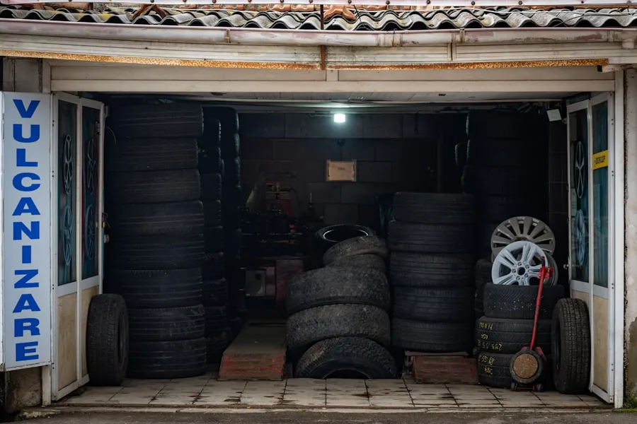 Ilustrasi mimpi tambal ban — Tire shop interior with stacks of tires and rims