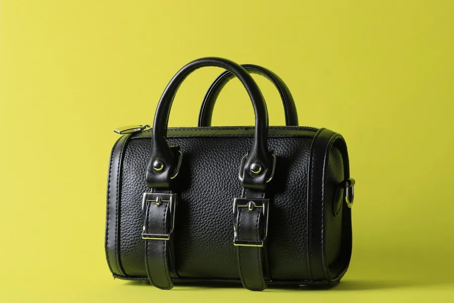 Ilustrasi mimpi tas tangan — a black leather bag on a yellow background