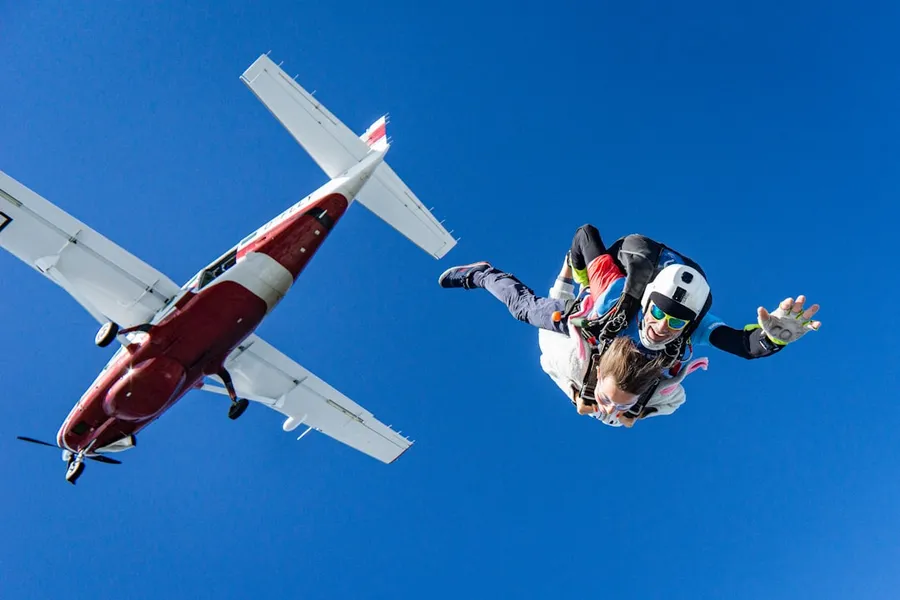 Ilustrasi mimpi terjun bebas — white and red airplane in mid air during daytime