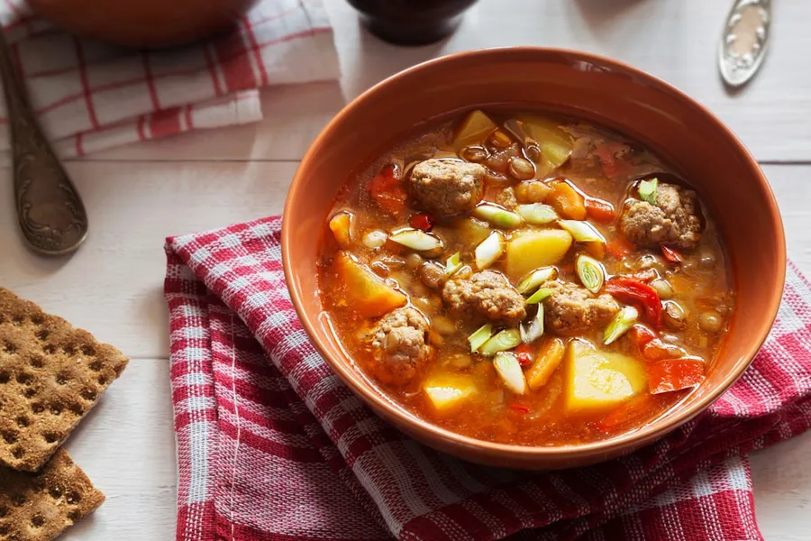 Ilustrasi mimpi tukang bakso — a bowl of soup with meatballs and vegetables