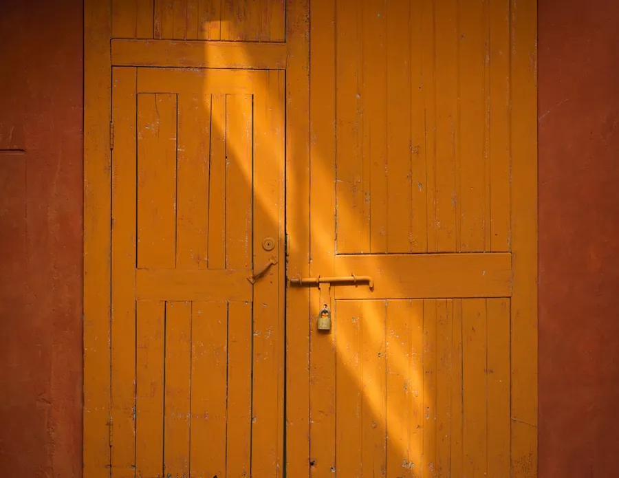 Ilustrasi mimpi xenophobia — A yellow door with a shadow of a person on it